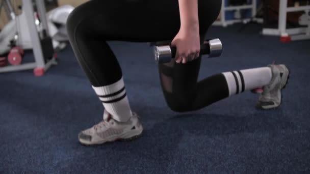 Fitness dziewczyna w stroju sportowym sprawia, że squat z bagażnika longe z hantlami w rękach. — Wideo stockowe