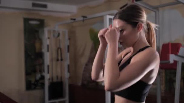 Passar ung kvinna i en sport svit värma upp innan du gör boxning träning på gymmet, medium shot. — Stockvideo