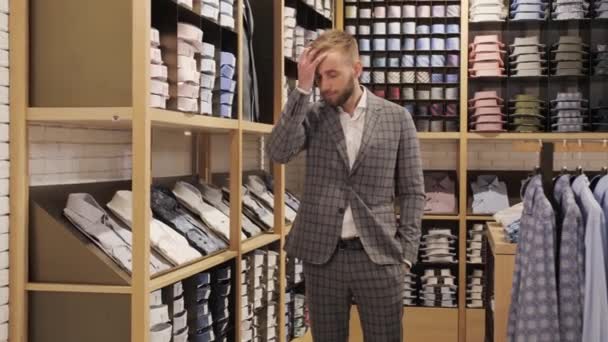 Gri takım elbiseli yakışıklı bir adam sakallı, erkek giyim mağazasında saçını düzeltiyor.. — Stok video