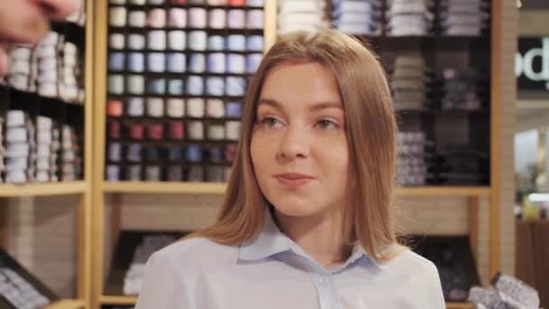 Una consultora femenina ayuda a un cliente a elegir una camisa en una tienda de ropa de marca . — Vídeos de Stock