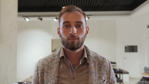 Un hombre elegante en un traje con barba empuja la cortina al probador en una tienda de ropa para hombres . — Vídeo de stock