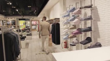 Elinde bir torbayla alışveriş yaptıktan sonra tatmin olmuş müşteri markalı kıyafet dükkanını terk ediyor..