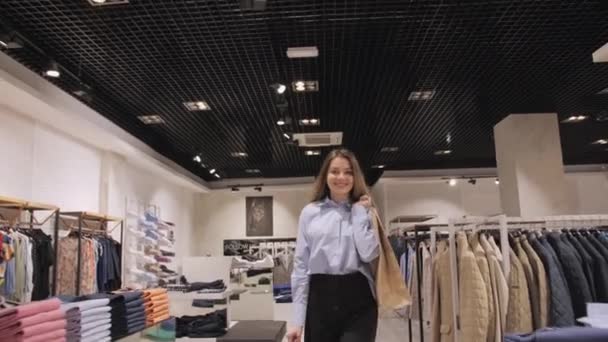 Gadis bahagia dengan paket di tangan meninggalkan toko setelah belanja. — Stok Video