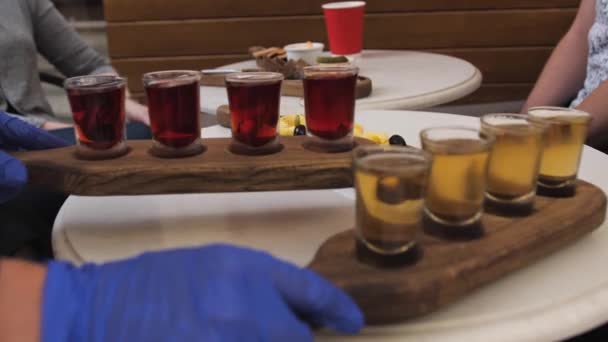 Ο σερβιτόρος με τα μπλε γάντια βάζει δύο σετ ποτά στο τραπέζι.. — Αρχείο Βίντεο