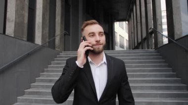 Genç bir işadamı telefonda modern bir bina yöneticisinin arka planında telefon iş merkezinde konuşuyor..