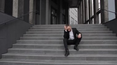 Kovulmuş bir ofis çalışanı merdivenlerde oturur ve kriz anında kafasını tutar..