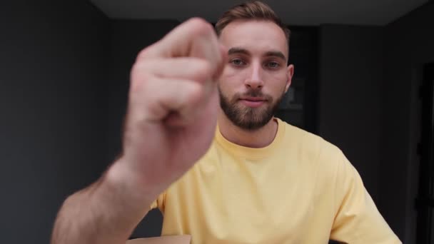 Mensajero en una camiseta amarilla entrega mercancías con comida proveedor de entrega en línea llama a la puerta . — Vídeos de Stock