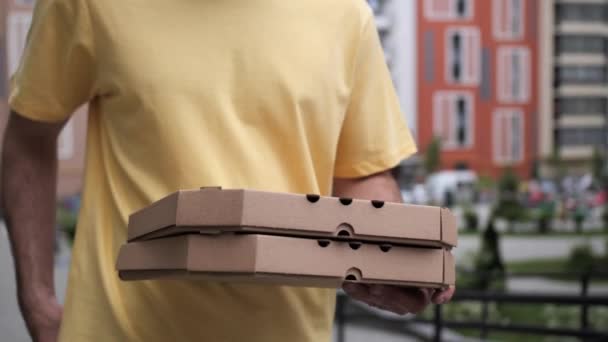 Kureren i en gul t-shirt har pizza. Leverandøren udfører ordren på pizza levering. – Stock-video