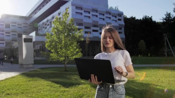 Menina bonita falando via webcam no laptop com seu amigo ao ar livre distância de aprendizagem . — Vídeo de Stock