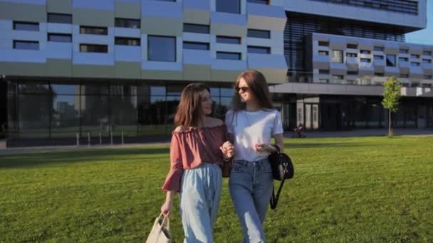 Zwei fröhliche Freundinnen gehen von der Universität und lachen. — Stockvideo