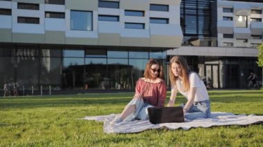 İki kız kardeş, modern binanın arka planındaki bir laptopta uzaktan ders çalışıyor..