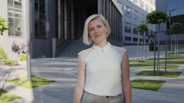 Ritratto di una bella donna d'affari di successo che guarda la macchina fotografica sullo sfondo del centro dell'ufficio. Vestito da donna bionda. Donna di successo. — Video Stock