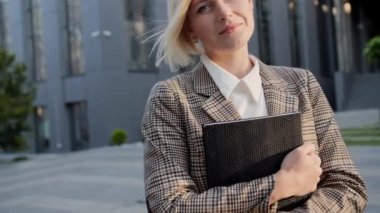 Yakışıklı sarışın elinde bir defterle kameraya bakıyor ve ofis merkezinin arka planında gülümsüyor başarılı bir kadın..
