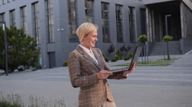 İnternet kamerasında konuşan güzel sarışın kadın ofis arka planında dizüstü bilgisayar kullanıyor. İş kadını video görüşmesinde konuşurken gülüyor..