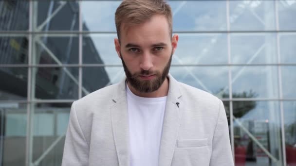 Portrait of a young businessman with a beard on the background of a modern glass building.Successful people, business concept. — Stock Video