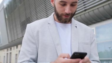 Amerikan tarzı çekici bir adamın telefon kullanmasına yakından bakın. Modern binanın yakınında kalın. Cep telefonu moda interneti..