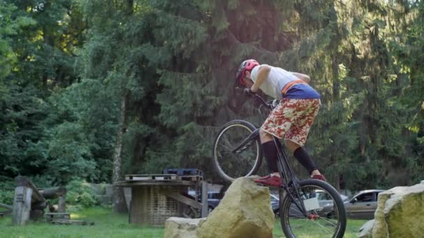 MTB, bicicleta, calle, chico practicando para hacer acrobacias Ciclismo extremo. El ciclista salta sobre una barrera desde una gran piedra contra una luz de fondo. — Vídeos de Stock