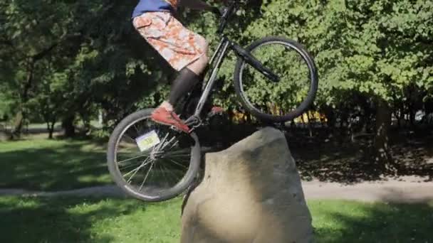 MTB, bike, street, boy practicing to do stunts Extreme cycling. The cyclist jumps on a barrier from a big stone against a backlight. — Stock Video