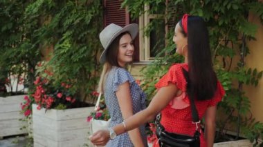 Şehir merkezinde çiçekli güzel bir evin yanında gülen en iyi iki bayan arkadaş... gülerek birbirlerini kucaklıyorlar..