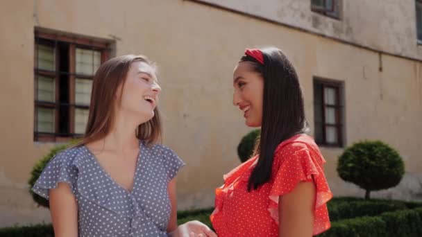 Retrato vista de dos mejores hermanas alegres en un aspecto elegante divirtiéndose en la calle urbana, posando a la cámara, abrazando. — Vídeo de stock