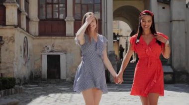 En iyi iki arkadaş el ele tutuşup gülüyorlar ve eski şehrin arka planında yürüyorlar..