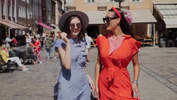 Dua pacar dengan gaun musim panas yang indah berjalan di sekitar kota dan bersenang-senang. Jalanan penuh kafe dan orang-orang. — Stok Video
