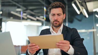 Yönetici işadamı ofis belgelerinden rahatsız edici haberler alıyor. Endişeli profesyonel, modern bir ofiste bir masada oturuyor, içeriği altında eziliyor, üzüntü ve hayal kırıklığını gösteriyor..