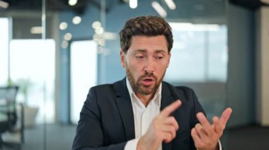 Modern ofiste başarılı bir iş adamı karmaşık proje fikirlerini özgüvenle açıklıyor. Kararlı profesyonel anlamlı jestler yapar, ciddi kararlılığı ve etkili iletişimi aktarır.