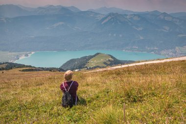 Otların arasında oturan ve Alpler üzerinde seyir genç kız.