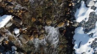 Kuzey nehri kışı köpüklü su sıçratıyor. Üst görüntü drone karlı göl 4K.