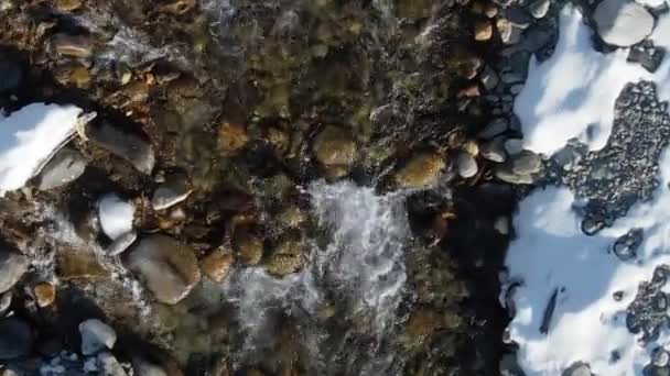 Splashing foam stream water northern river winter. Vue du dessus drone lac neigeux 4K.