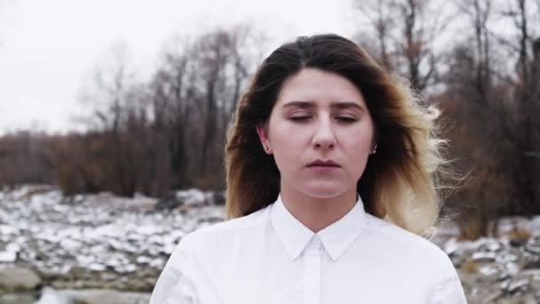 Mujer ojos abiertos primer plano en camisa blanca rocosa río de invierno. Persona cara tranquila 4K . — Vídeo de stock