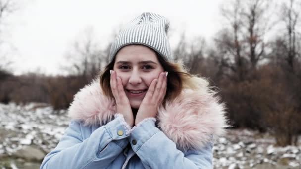 Ragazza giocosa tenere la mano faccia e ruotare la testa bel sorriso. Foresta eolica fredda 4K. — Video Stock