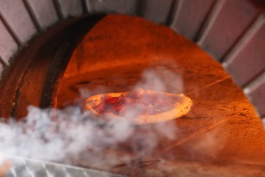 Odun ateşinde Napoli pizzası pişirmek.