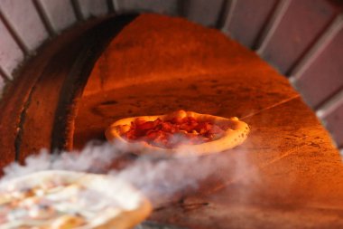 Odun ateşinde Napoli pizzası pişirmek.