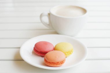 cup of latte with macaroons plate on wooden background 