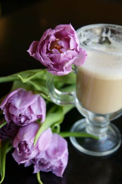 Sıcak bir fincan latte ve bir buket çiçek.