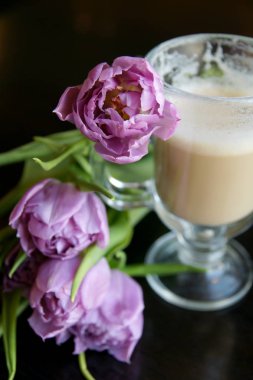 Sıcak bir fincan latte ve bir buket çiçek.