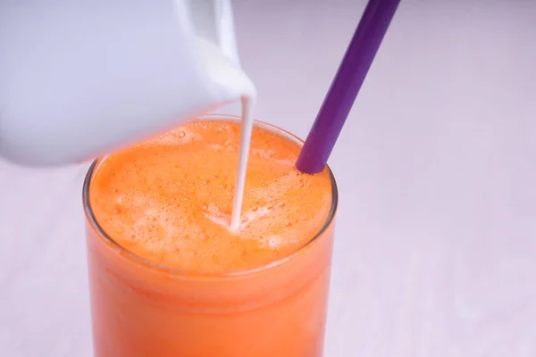 glass of fresh carrot juice with milk on wooden table