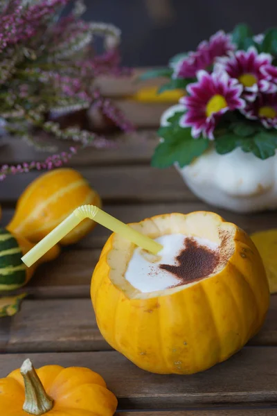 Coffee in pumpkin on a wooden table.