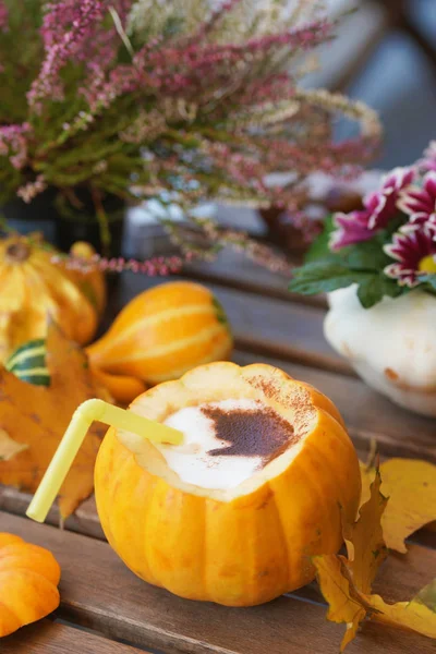Coffee in pumpkin on a wooden table.