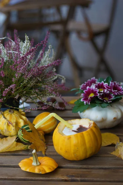 Coffee in pumpkin on a wooden table.