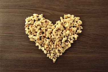 Ahşap masa üzerinde patlamış mısır ile yapılan kalp. Sinema seven kavramı. Üstten Görünüm