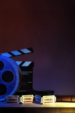 Ekipman ve ahşap masa ve koyu mavi arka plan sinema unsurları. Film izlerken kavramı. Dikey kompozisyon. Önden görünüm.