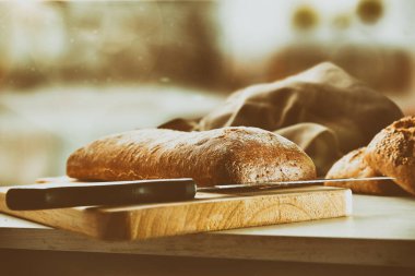Tüm somun ekmek kesme tahtası geleneksel eski bir mutfak tezgah üzerinde. Önden görünüm. Yatay kompozisyon