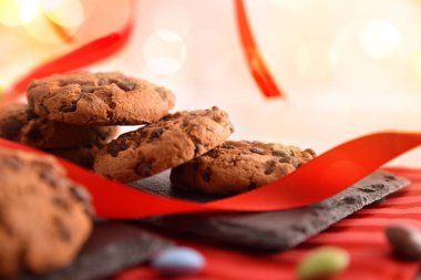 Kutlama üstünde şerit ve tatlılar ile dekore edilmiş kırmızı masa örtüsü ile beyaz tabloda kayrak tepsi çikolata kurabiye ile kapatın. Önden görünüm. Yatay kompozisyon