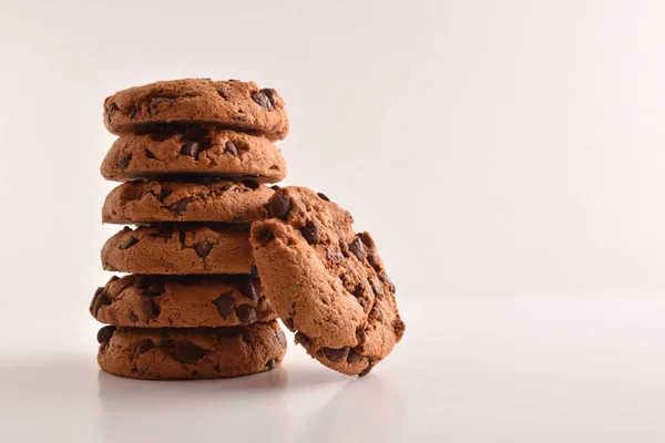Stack of cookies with chocolate chips on table and white background. Front view. Horizontal composition