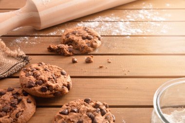 Rustik bir mutfak malzemeleri Ahşap çıtalı masada çikolata parçaları ile ev yapımı kurabiyeler. Yatay kompozisyon. Yükseltilmiş görünümü