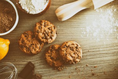 Ev yapımı kurabiye bir rustik mutfak vintage malzemelerle ahşap masa üzerinde çikolata parçaları ile. Yatay kompozisyon. Üstten görünüm