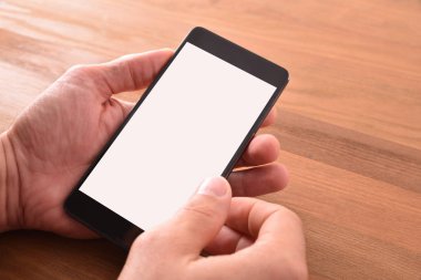 Ellerini bir adamın elinde kahverengi ahşap izole masada taşınabilir telefon ile. Yükseltilmiş görünümü. Yatay kompozisyon.